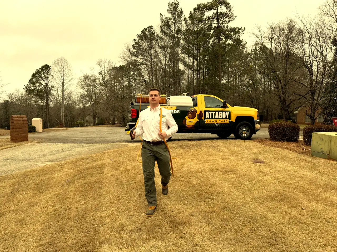 Attaboy Lawn Care professional approaching lawn for treatment