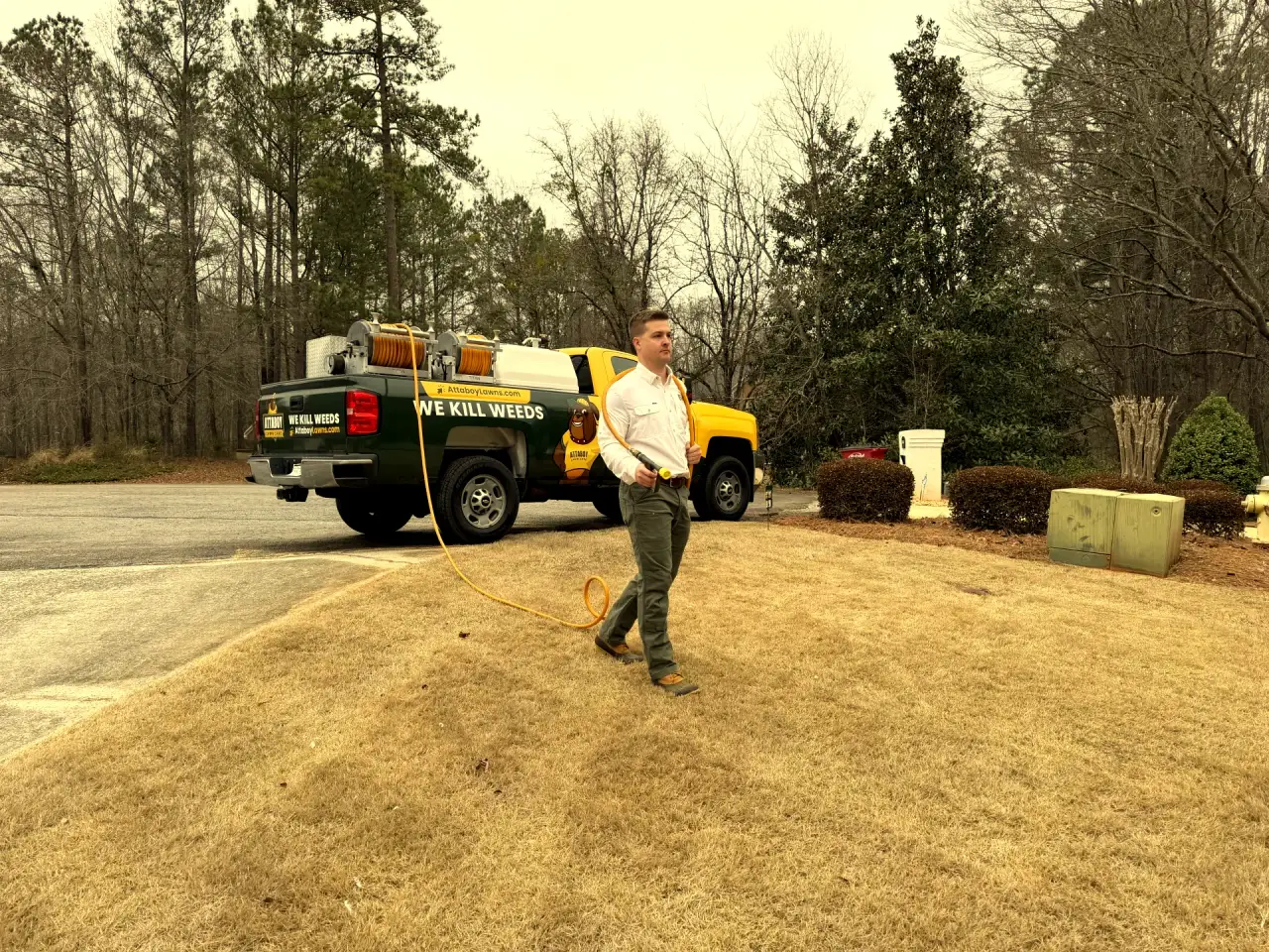 Attaboy Lawn Care technician applying weed control treatment to residential lawn in Central Georgia